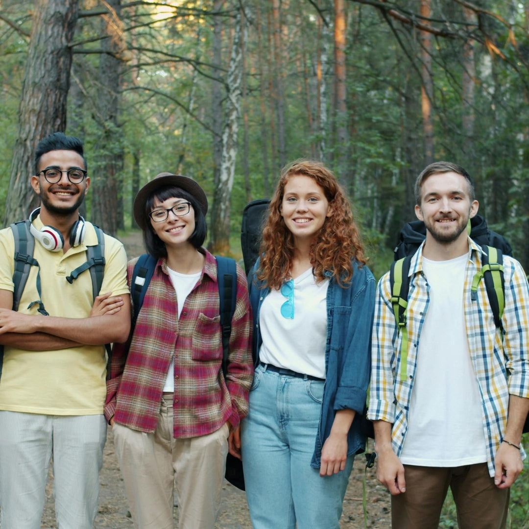 Four friends with backpacks standing in a forest